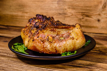 Baked piece of pork belly and parsley on a black plate