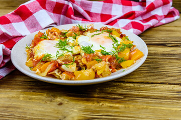 Homemade breakfast shakshuka with fried eggs, onion, bell pepper, tomatoes and dill on a wooden table. Jewish cuisine