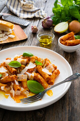 Noodles with pesto, parmesan cheese and basil leaves served on wooden table
