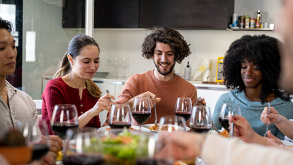 Young friends at the table while eating typical Italian food and spaghetti, meeting to celebrate an event and to be in company, concept of friendship and affective family