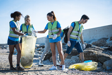 Young people cleaning up the beach, volunteers collecting the waste on the coast line, young people...