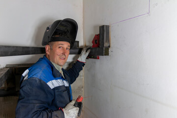 An experienced man   using a spirit level and welding a seam on a spiral staircase at a...