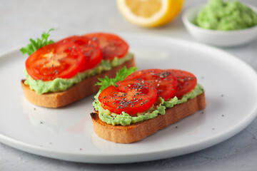 Vegan sandwich with avocado and tomatoes on a white dish