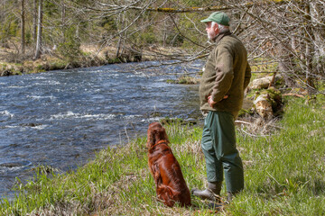 A hiker and his Irish Setter stand by the scenic Regen River. The gentle murmur of the water and...