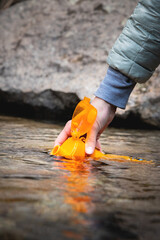 Close-up of female hands pouring drinking water from a mountain spring into a silicone bottle....