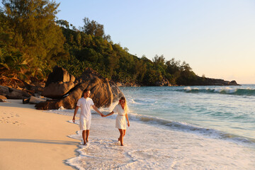 beautiful couple of lovers walks the Seychelles against the background of stones, splashes, holding hands © Ivan