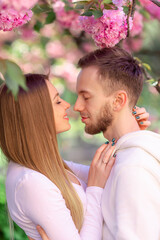 Sensual couple posing to camera with beautiful cherry blossoms in the background. Spring family look