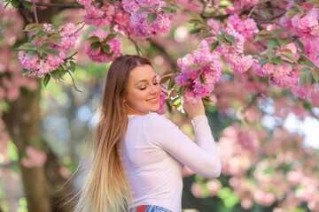 Sensual portrait of a charming blonde on the background of a blooming garden.