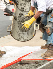 Wet cement off loaded by construction workers from a cement truck chute into a concrete form with...