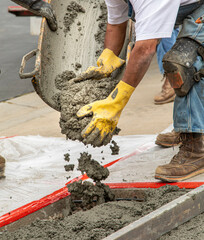 Wet cement off loaded by construction workers from a cement truck chute into a concrete form with rebar