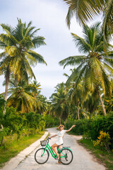 Girl with a old vintage bicycle on a background of palm trees. young woman in rainforest jungle with palm trees. relaxed sightseeing and tourist activities summer vacations