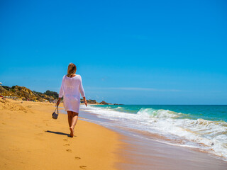 Beautiful woman walking on sunny beach
