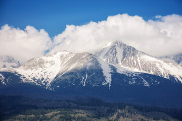 nature background of mighty high tatra ridge in spring at high noon. snowcapped rocky peaks beneath a cloudy sky
