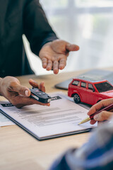 Employee of the rental car company handing over the keys to the renter after discussing the details and conditions of the contract with the customer who signed the insurance. - obrazy, fototapety, plakaty