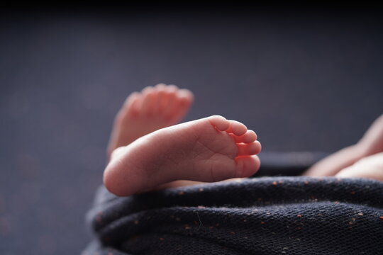 Tiny baby foot on navy blue background blanket.close up View of baby foot the baby is wrapped comfortably in a blue blanket.