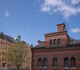 Fototapeta na wymiar Roof, dorms and chimney on the old royal stable brick houses in the district Östermalm, a sunny spring day in Stockholm