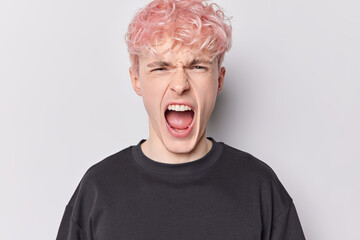 Human reactions and negative emotions concept. Emotional pink haired European man shouts loudly keeps mouth opened expresses rage and irritation dressed casually isolated over white Generative AI - obrazy, fototapety, plakaty