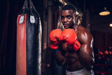 Boxing training of athlete african american man punching a bag at muay thai gym. Active male...