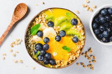 Smoothie Bowl with Orange, Kiwi, Banana, Blueberry, and Granola in a Coconut Bowl, Healthy Food Concept