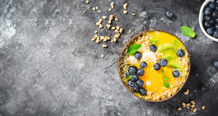 Obraz na płótnie Canvas Smoothie Bowl with Orange, Kiwi, Banana, Blueberry, and Granola in a Coconut Bowl, Healthy Food Concept