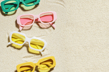 Fototapeta na wymiar Set of colorful sunglasses on beach sand background at sunlight with shadow. Summer fashion eyeglasses with colored glass. Summer vacation, summer rest concept. Minimal flat lay, copy space