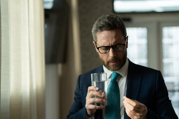 Tired man suffering from headache after computer work, exhausted with closed eyes touching head, relieving pain, migraine. Man taking a Medicine pill from headache migraine.