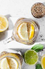 Chia Infused Water with Lemon and Lime in Jars, Healthy Citrus Drink on Bright Background
