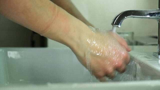 A girl in a blue medical suit washes hands. It soap with soap and carefully cleanses under the dda under the tap. Covid, Epivate. High quality FullHD footage Generative AI