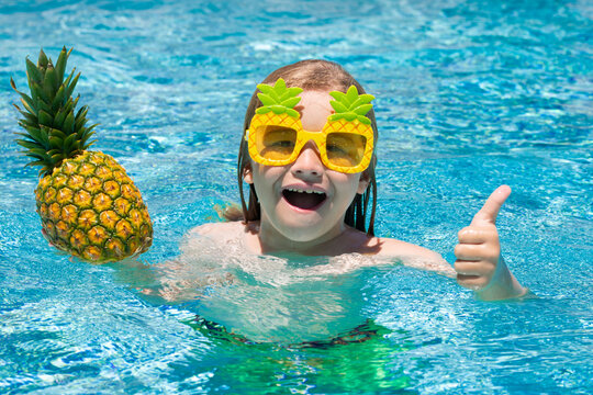 Funny little boy relaxing in a swimming pool, having fun during summer vacation in a tropical resort.