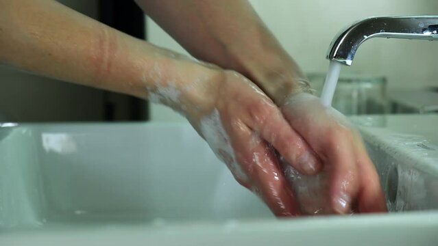 A girl in a blue medical suit washes hands. It soap with soap and carefully cleanses under the dda under the tap. Covid, Epivate. High quality FullHD footage Generative AI