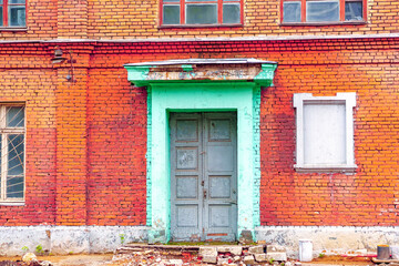 Fototapeta na wymiar The facade of an old abandoned brick building with a wooden door