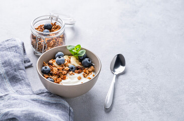 Muesli with vegetarian yogurt, banana and blueberries in a bowl on a light background. Healthy and dietary homemade granola for breakfast.