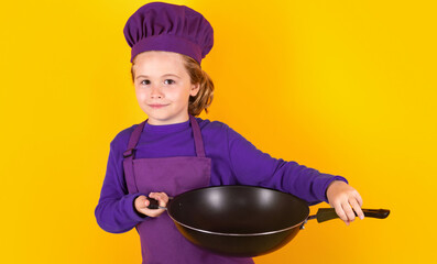Kid cook with cooking pan. Portrait of little child in uniform of cook. Chef boy isolated on studio background. Cute child to be a chef. Child dressed as a chef hat.