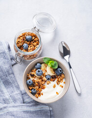 Muesli with vegetarian yogurt, banana and blueberries in a bowl on a light background. Healthy and dietary homemade granola for breakfast.
