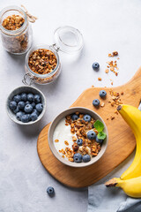 The concept of a healthy breakfast of yogurt, granola and fresh blueberry and banana on a light background. Homemade diet and protein food.