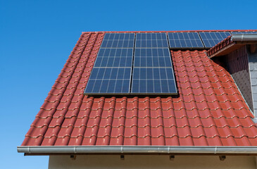 photovoltaic power plant or solar panels on a red tiled roof, blue sky, no clouds