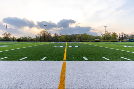 Dramatic late afternoon photo of the 50 yard line on a synthetic turf football field.

