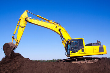 A large construction excavator of yellow color on the construction site in a quarry for quarrying