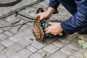 Elderly experienced male professional worker, electrician, electromechanic repairs an old rusty...