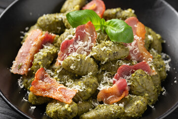 Italian potato gnocchi with green pesto sauce, bacon and parmesan cheese. Healthy food