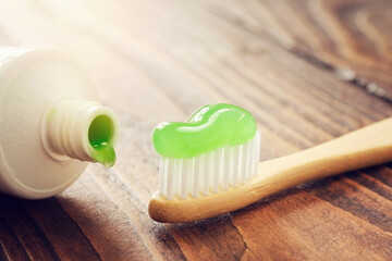 Eco friendly wooden bamboo toothbrush with toothpaste and tube of herbal toothpaste closeup. - 598138458