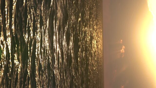 Picturesque seascape with small waves in golden sunset light, vertical video. Generative AI