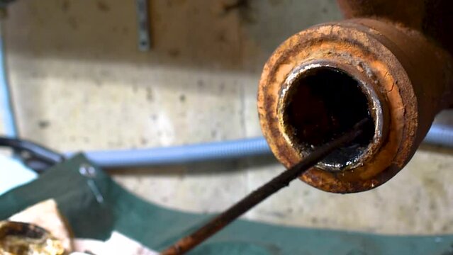 Hands of a plumber as he runs a camera scope and cleaning machine through the main pipe to unclog the drain to the Septic System. Hard-working tradesman.