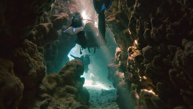 Diving in a coral canyon or cave with a group of divers in the red sea in egypt, slow-motion
