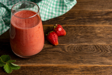 Glass of fresh strawberry milkshake, smoothie and fresh strawberries wooden background.