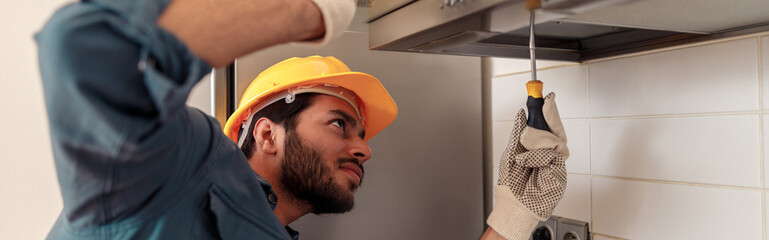 Service man repairing kitchen extractor, replacing filter in cooker hood. High quality photo