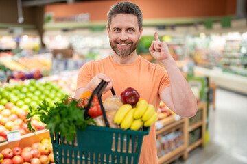 Man with fruits and vegetables at grocery store. Healthy food for mens health. Man with shopping cart full of fresh vegetables. Man at grocery store or supermarket.