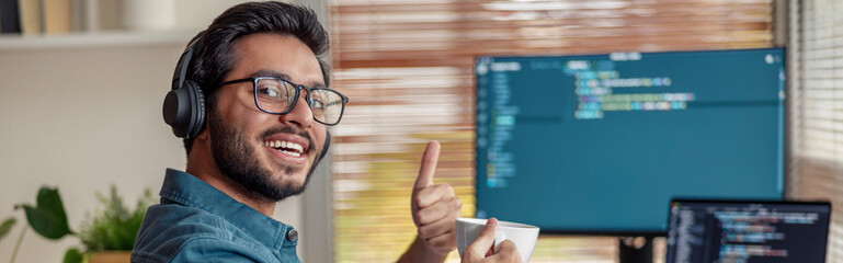 Man in headphones freelance data scientist work remotely at home and looking at camera