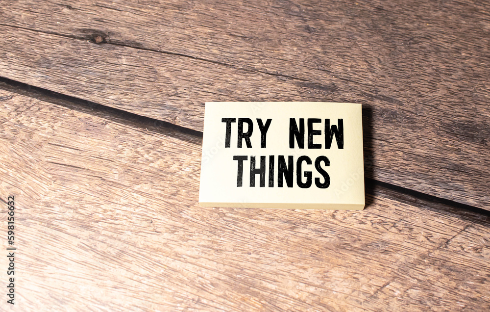 Poster notepad with text try new things in the wooden background.