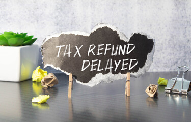 Sticky note with the text Tax Refund Delayed on Income Tax form background with calculator